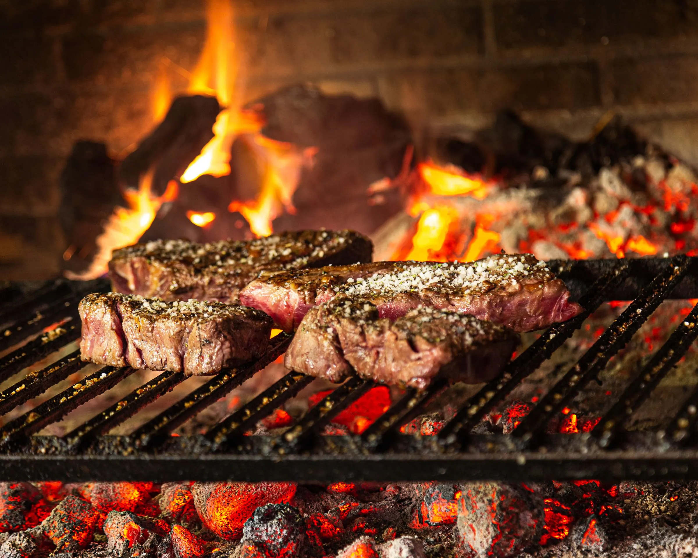 Txuletas de vaca vieja asándose sobre brasa de leña en el asador